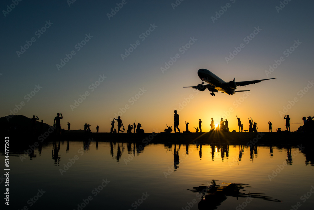 Silhouette airplane and people while landing gear is down during sunset hours 