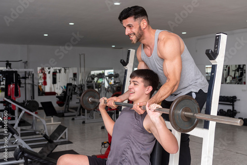 gym instructor teacher teaching a young student how to train with barbell in a gym photo
