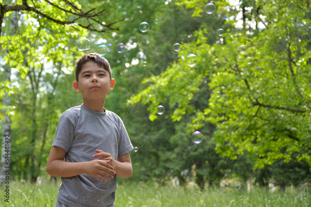 Child catches soap bubbles in the park in summer Child catches soap bubbles in the park in summer