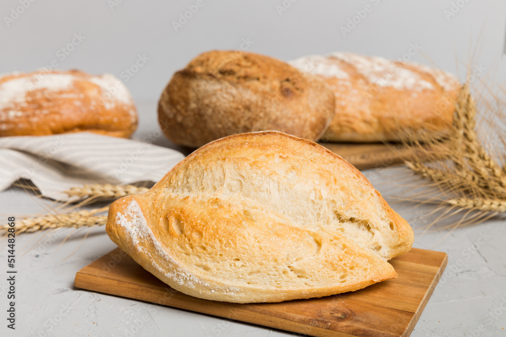 Freshly baked bread on cutting board against white wooden background. perspective view bread with copy space