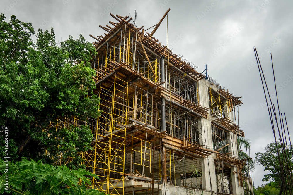 Unfinished building after rain. Construction site with scaffolding against the background of thunderclouds. Construction without workers.