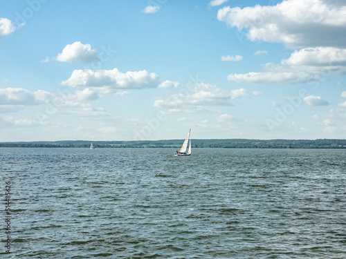 White sailboat on the lake. Daytime landscape.