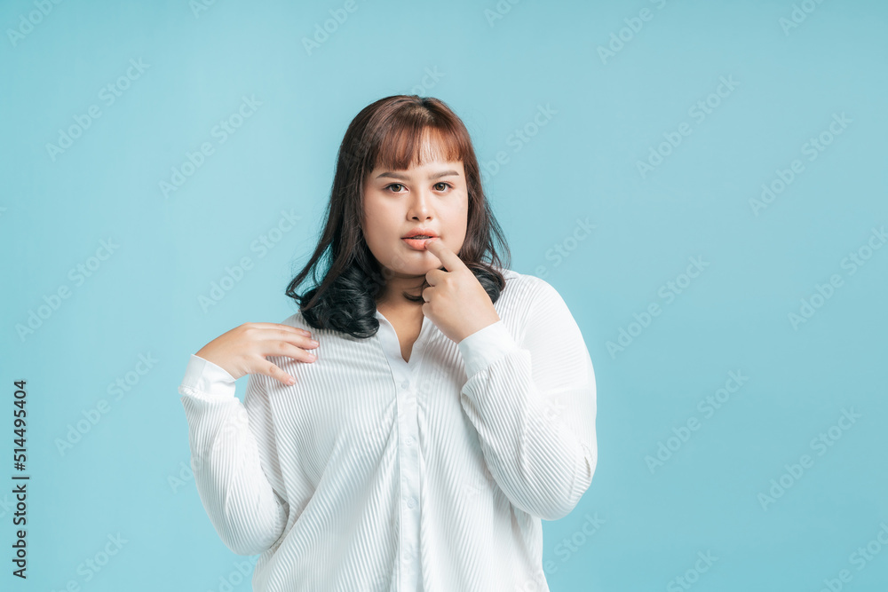 Portrait beautiful confidence Asian woman plus size model posing on isolate light blue studio background. Young female chubby confident concept. Portrait beautiful confidence Asian woman plus size model posing on isolate light blue studio background. Young female chubby confident concept.