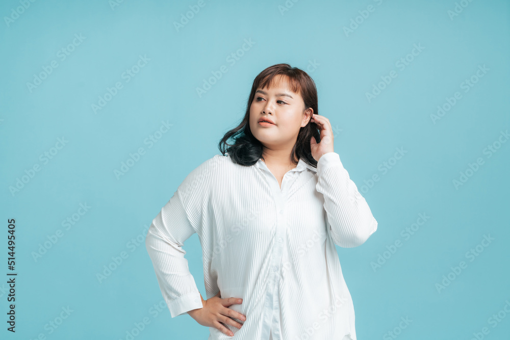 Portrait beautiful confidence Asian woman plus size model posing on isolate light blue studio background. Young female chubby confident concept. Portrait beautiful confidence Asian woman plus size model posing on isolate light blue studio background. Young female chubby confident concept.