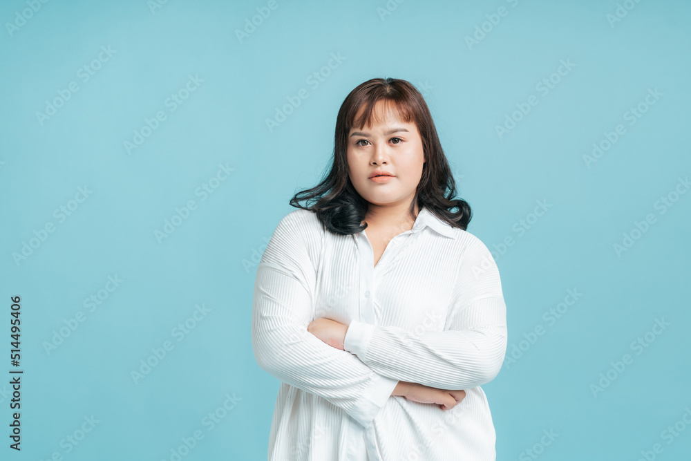 Portrait beautiful confidence Asian woman plus size cross arms on isolate light blue studio background. Young female chubby confident concept. Portrait beautiful confidence Asian woman plus size cross arms on isolate light blue studio background. Young female chubby confident concept.