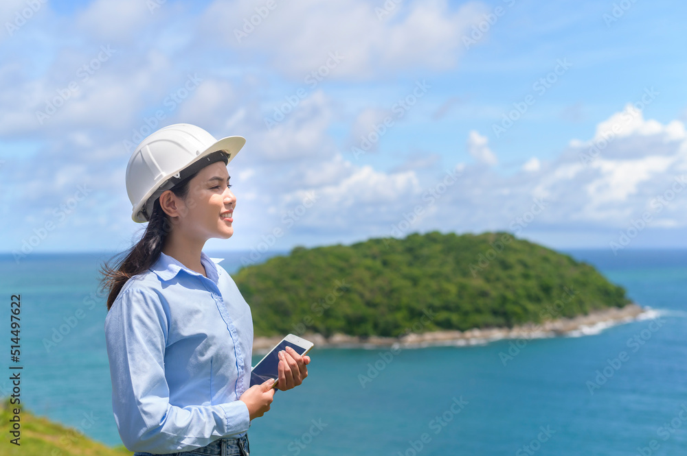 Female engineer working on the seaside wearing a protective helmet .