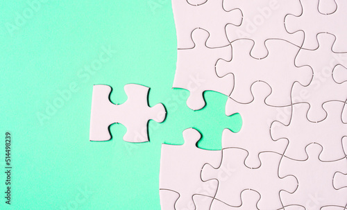 White jigsaw puzzle with some missing pieces on green background. Flat lay.