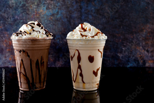 Milkshakes of different flavors in clear glass on a dark background.