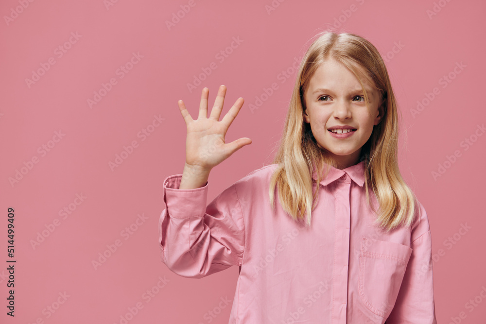 cute, beautiful, happy girl in pink clothes posing in the studio on a pink background showing five fingers and smiling broadly