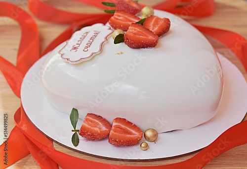 red strawberry on a heart-shaped cake. Valentine's Day. inscription in Russian we wish you happiness