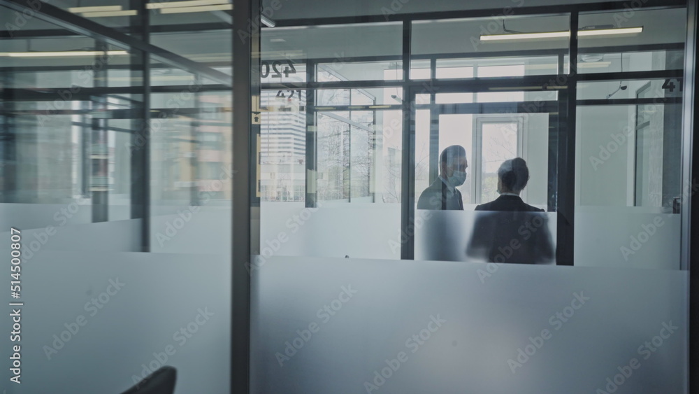 Company employees in face masks talking in office corridor, work during pandemic Company employees in face masks talking in office corridor, work during pandemic