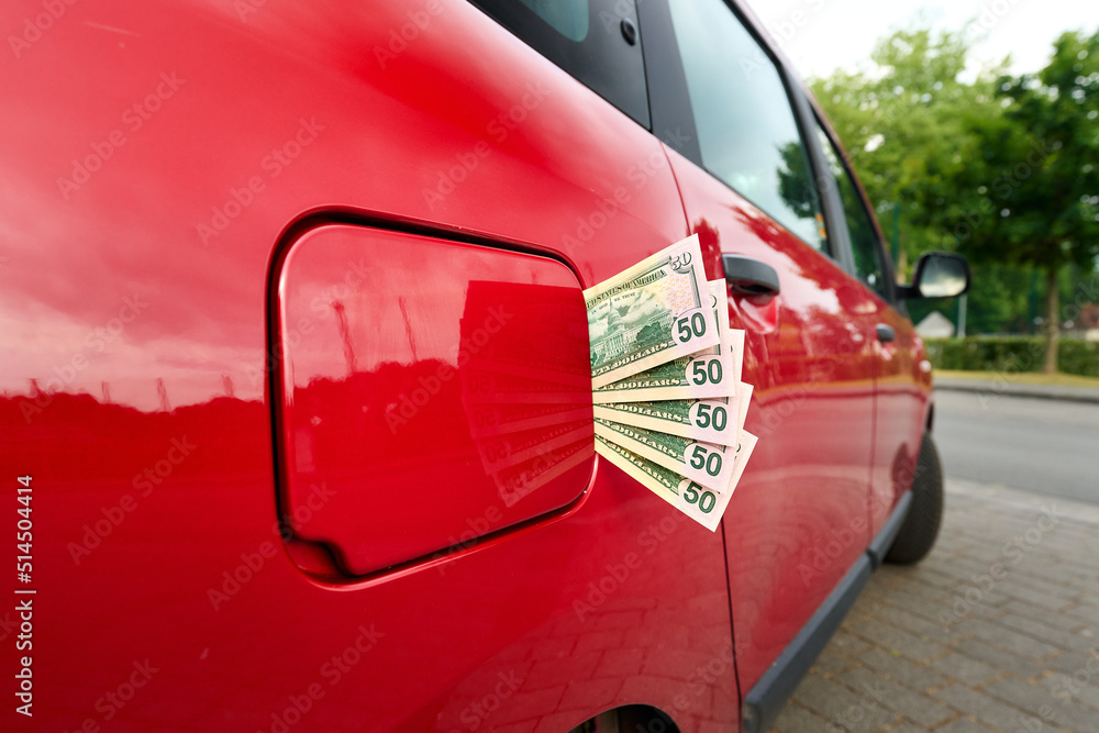 Naklejka premium Fifty dollar notes sticking out of a car's closed fuel tank