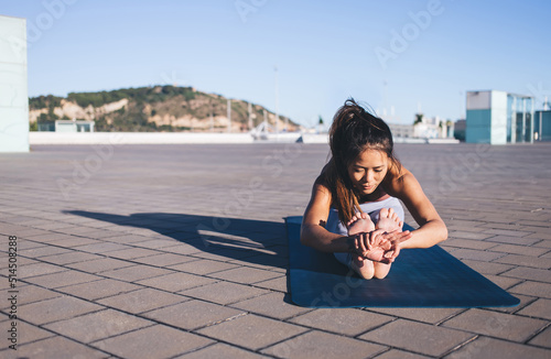 Фотография Flexible female yogi practicing yoga pose during stretching workout at urban set