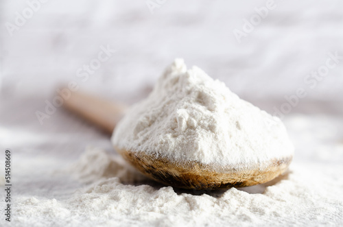 A spoonful of white flour on wooden backdrop. Close-up.