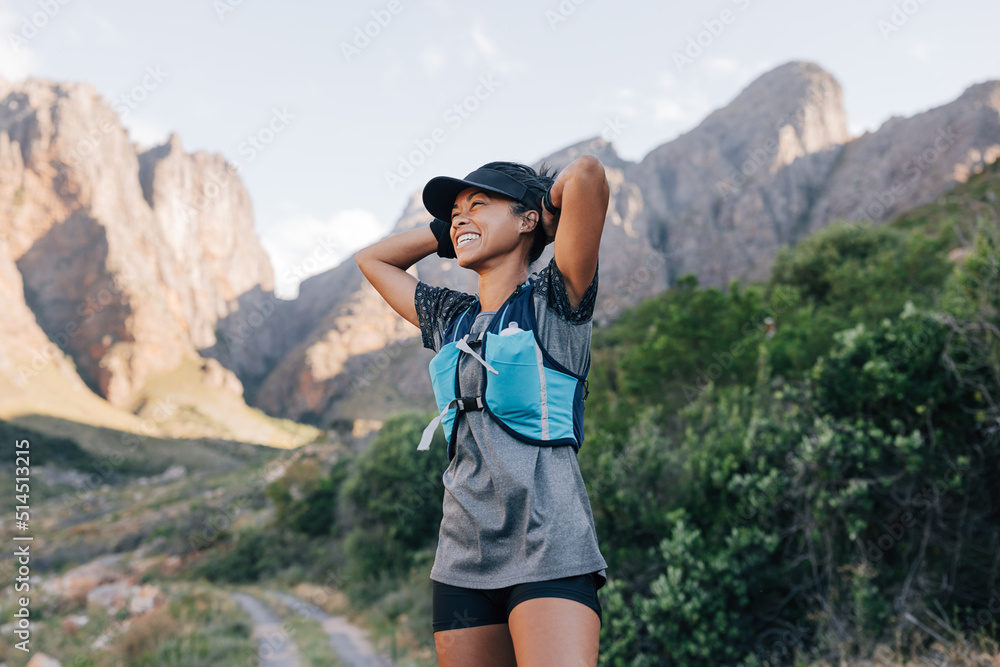 Obraz premium Laughing woman in sportswear relaxing during hike. Smiling female in wild terrain looking away.