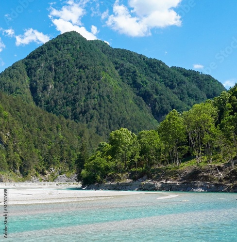 Mountain landscape with green forest, shoreline, blue sky and water. Deserted island concept.