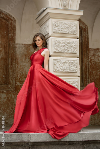 Beautiful fashionista in a red flowing long dress. City walks
