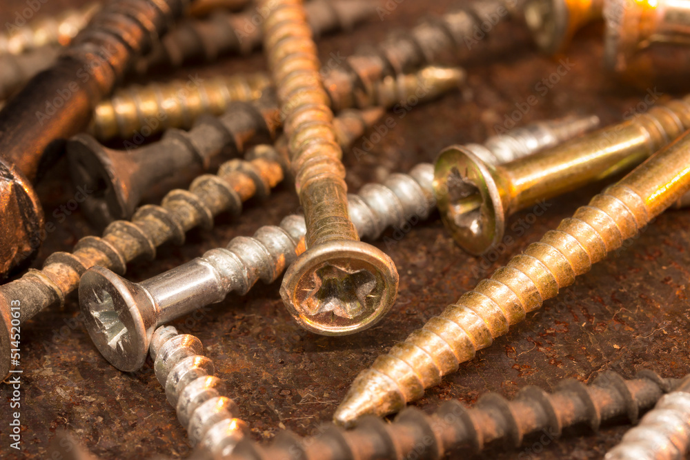 Screws on rusty textured metal surface close-up. Warm red orange brown color scheme. Industrial background. Screws on rusty textured metal surface close-up. Warm red orange brown color scheme. Industrial background.