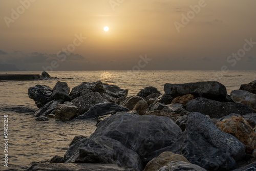 Sonnenuntergang am Meer in Italien. Vielfalt der Farben und Farben der aufgehenden Sonne. Meereslandschaft mit Wasser und Steinen.