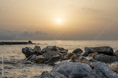 Sonnenuntergang am Meer in Italien. Vielfalt der Farben und Farben der aufgehenden Sonne. Meereslandschaft mit Wasser und Steinen.