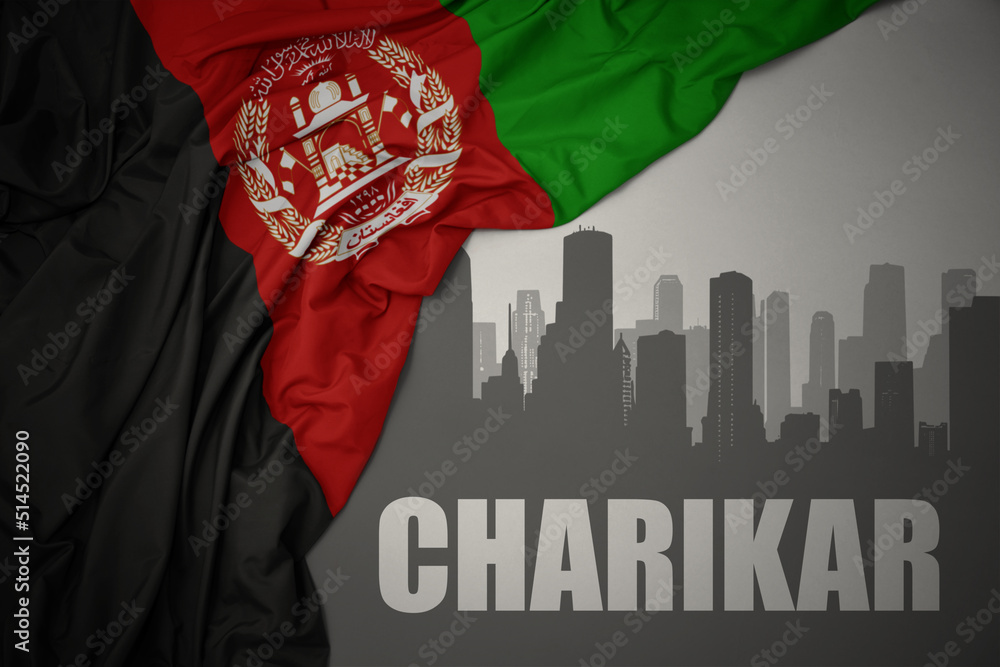 abstract silhouette of the city with text Charikar near waving national flag of afghanistan on a gray background.