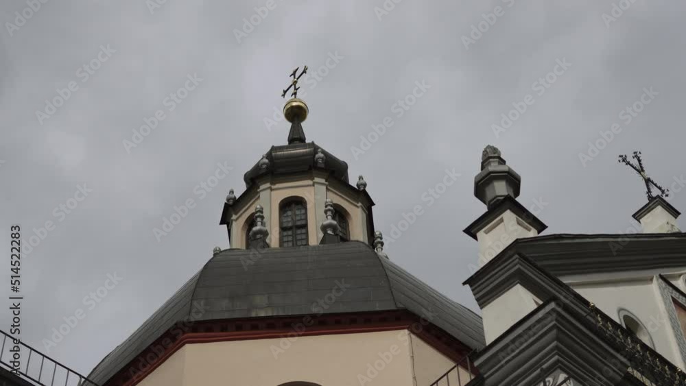 Beautiful dome with windows and cross on old baroque Catholic church against gray sky with clouds in sunlight. Facade of the temple. Beautiful dome with windows and cross on old baroque Catholic church against gray sky with clouds in sunlight. Facade of the temple.