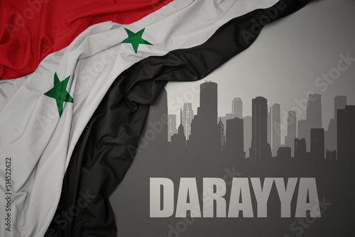 abstract silhouette of the city with text Darayya near waving national flag of syria on a gray background. photo