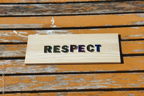 RESPECT in rainbow lettering on rustic orange wood background
