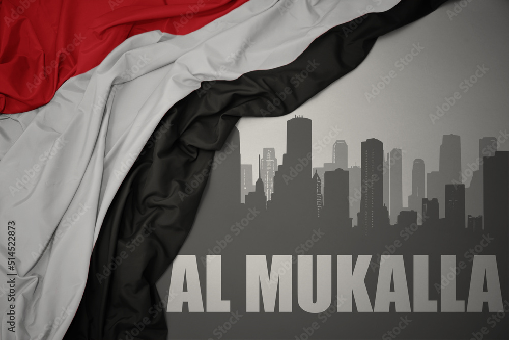 abstract silhouette of the city with text Al Mukalla near waving national flag of yemen on a gray background.