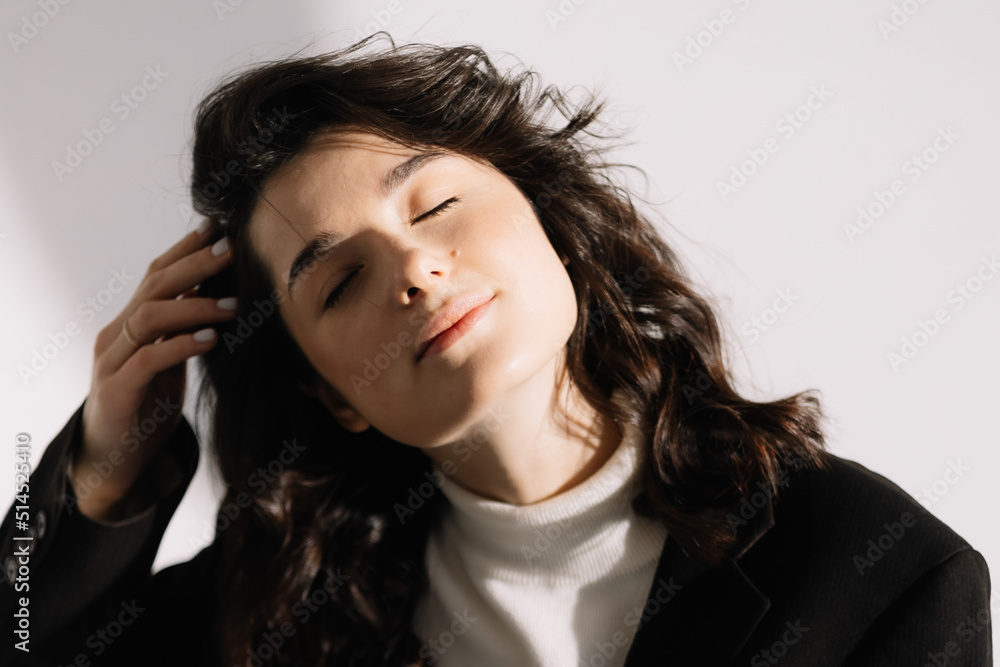 Fashion studio photo of stylish European brunette woman in in long baggy pants and a black jacket posing on white background. Trendy office style in clothes. Fashion studio photo of stylish European brunette woman in in long baggy pants and a black jacket posing on white background. Trendy office style in clothes.