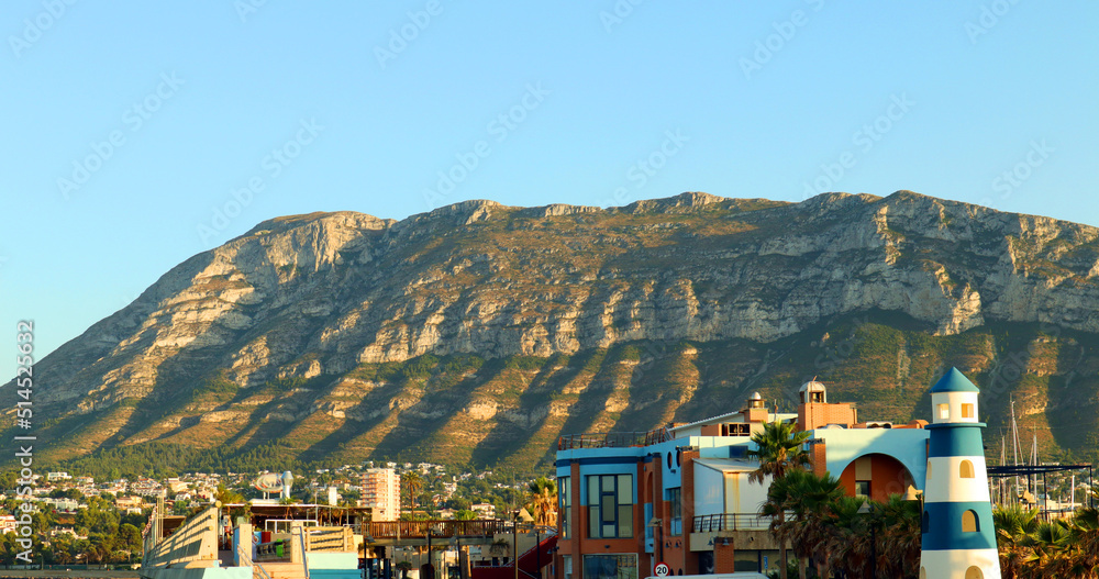 Denia Spain. View of Mount Montgo and the city from afar, beautiful colorful buildings, sunset, blue sky, summer