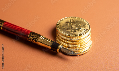 Bitcoin, bitcoin coins and a vintage fountain pen placed on a brown leather background, selective focus.