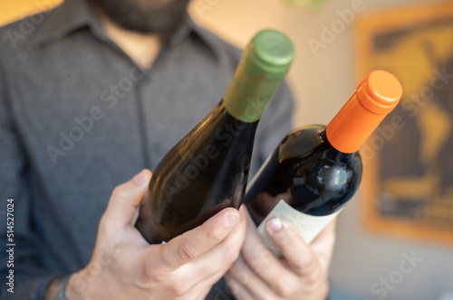 Adult man choosing beetwen two bottles of wine in a cozy place photo