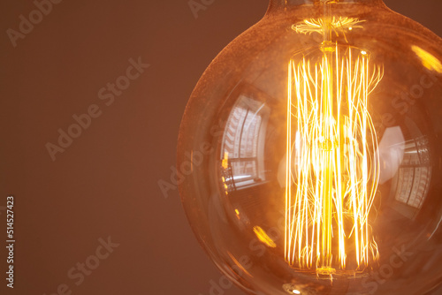 Fotografering Classic retro incandescent edison light bulb: close up of the glowing filament
