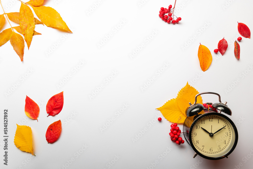 Yellow autumn leaves and an alarm clock on a white background, thematic layout, autumn offers in stores, hurry up