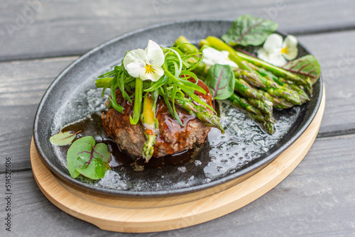 Hambagu (Hamburger Steak) with asparagus and green onion served on a cast iron pan