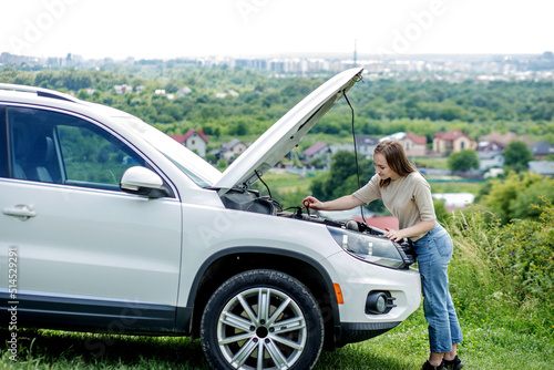 The woman pulls out a probe in her car engine to check the oil level. The woman manages the car herself © volody10
