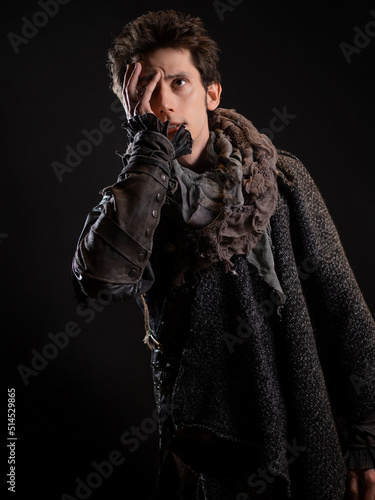 A guy in a steampunk or post-apocalyptic image, he covered his face with his hand. portrait on a black background