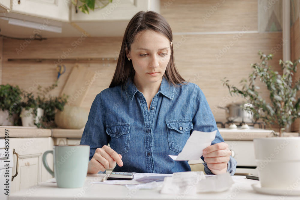 woman pays utility bills and writes checks. a European woman at home makes a calculation of expenses for a month. financial literacy and loan repayment. a woman calculates on the calculator the amount