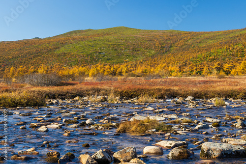 View of the shallow river and hills. Beautiful autumn landscape. Ecological tourism and wilderness travel. Amazing northern nature. Magadan region, Siberia, Russian Far East. Autumn season. September. photo
