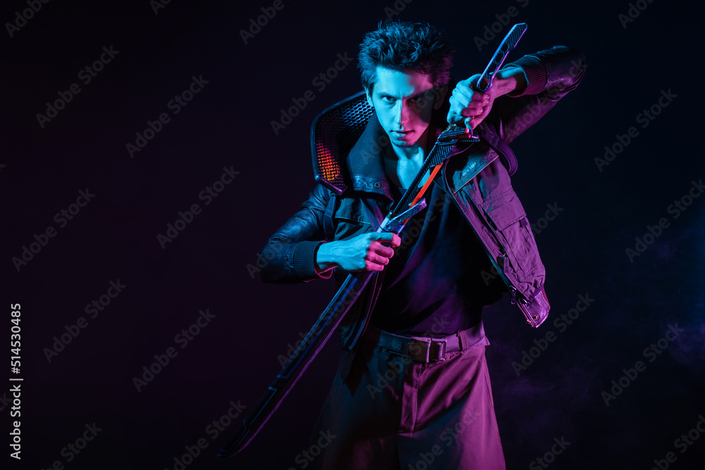 Fototapeta premium A guy in a cyberpunk image, holding a tuned sword in his hands. Cyborg samurai. A young man in neon lighting on a black background