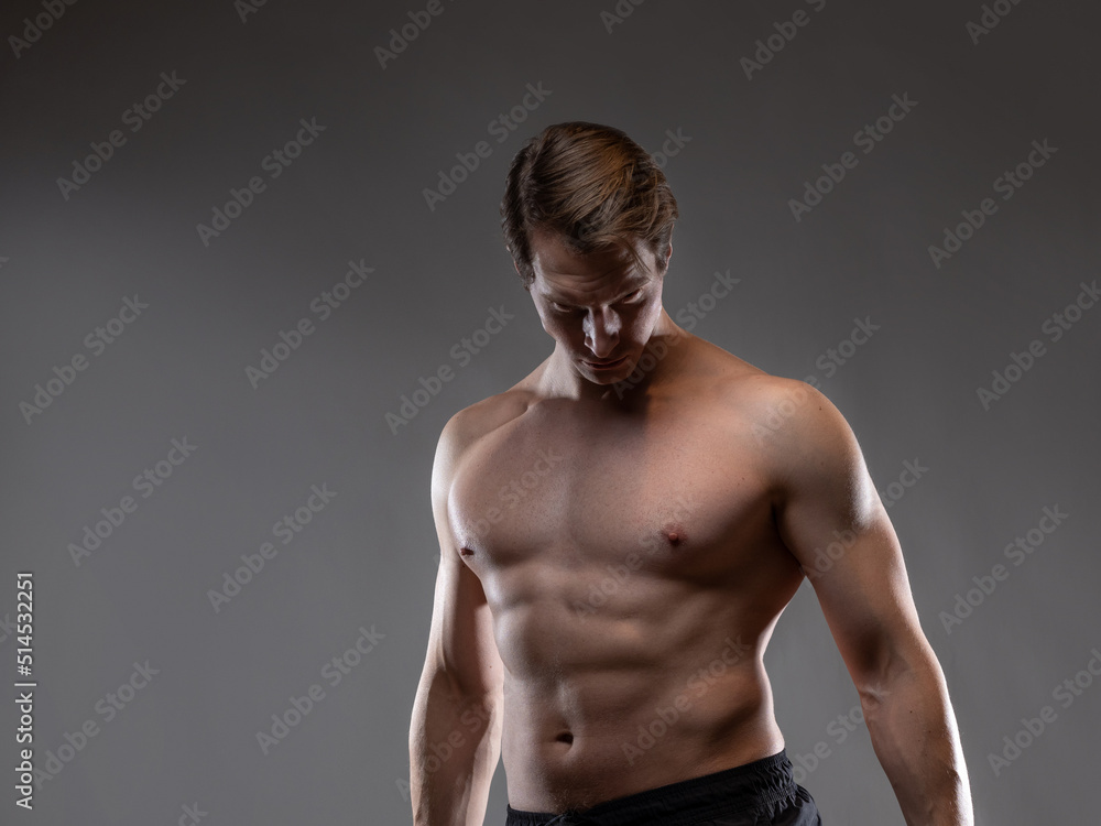 A muscular man expressively emotionally poses on a gray background. The guy is an athlete with pumped-up muscles. beautiful body relief. A muscular man expressively emotionally poses on a gray background. The guy is an athlete with pumped-up muscles. beautiful body relief.