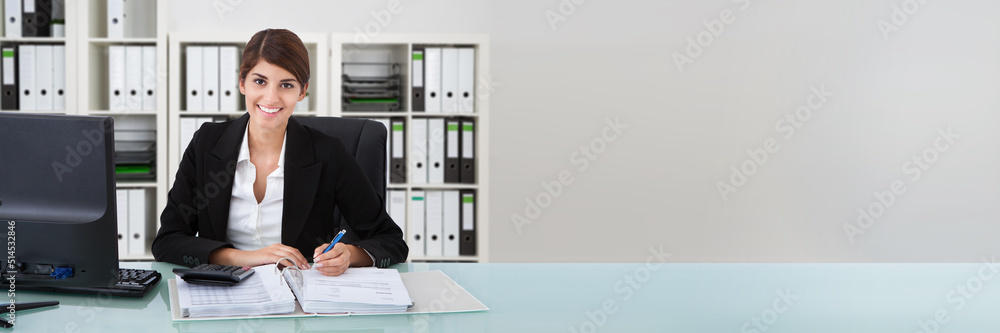 Confident Businesswoman Using Calculator At Office Desk Confident Businesswoman Using Calculator At Office Desk