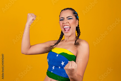 Brazilian supporter. Brazilian woman fan celebrating on soccer or football match on yellow background. Brazil colors.