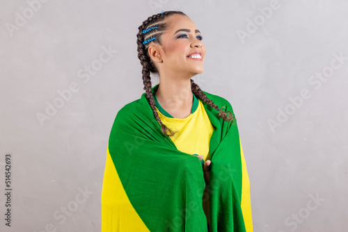 Brazilian fan holding Brazil flag on gray background. Young smiling brazilian woman smiling at camera with brazil flag