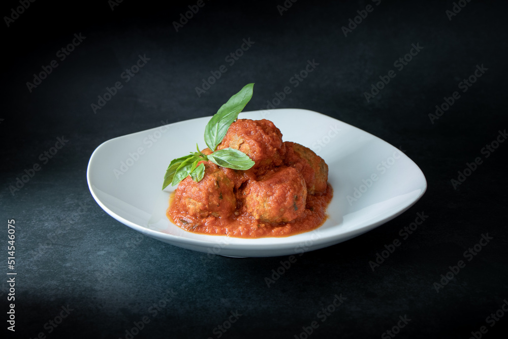 Italian meatballs seasoned with tomato sauce decorated with basil leaves Italian meatballs seasoned with tomato sauce decorated with basil leaves
