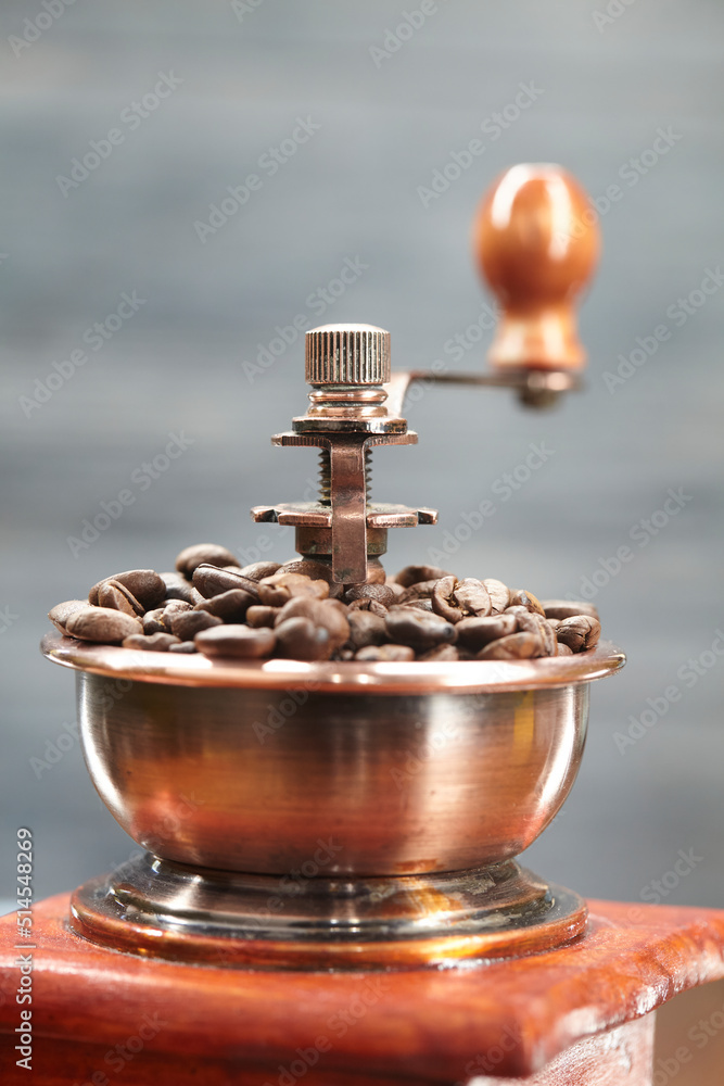 Granos de café en molinillo antiguo de madera y metal sobre fondo gris Granos de café en molinillo antiguo de madera y metal sobre fondo gris