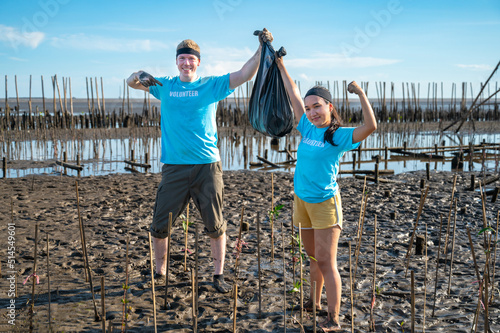 Couple showing hands holding black trash bag , Do not destroy the environment.Dirty people hands on blurred natural mangrove forest background.