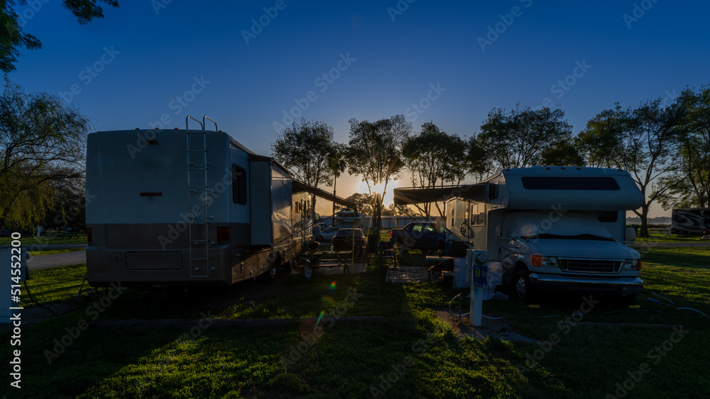 Sun rising early morning at campsites with Rv motorhomes and camper trailers parked door to door for companionship Sun rising early morning at campsites with Rv motorhomes and camper trailers parked door to door for companionship