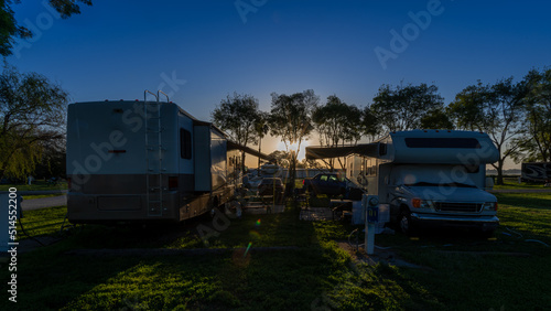 Sun rising early morning at campsites with Rv motorhomes and camper trailers parked door to door for companionship 